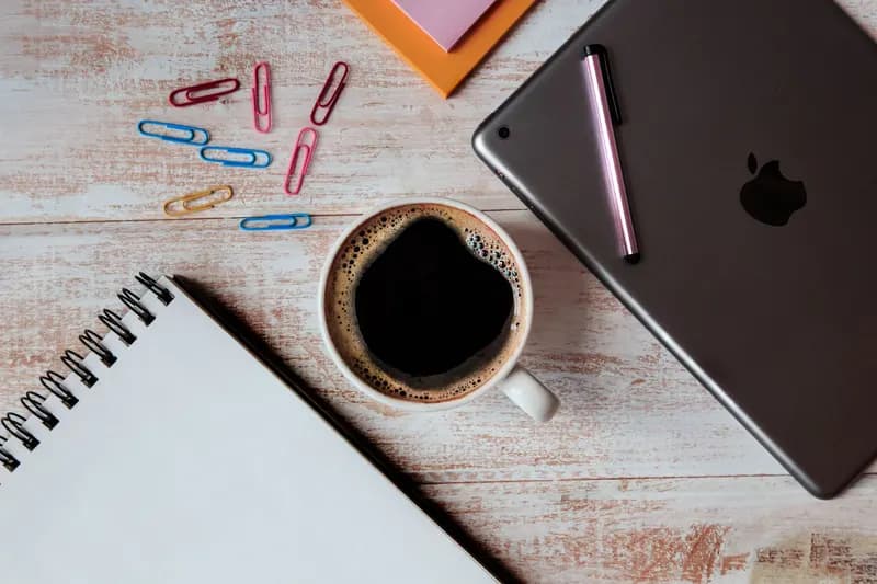 A tablet, coffee and paperclips on a desk